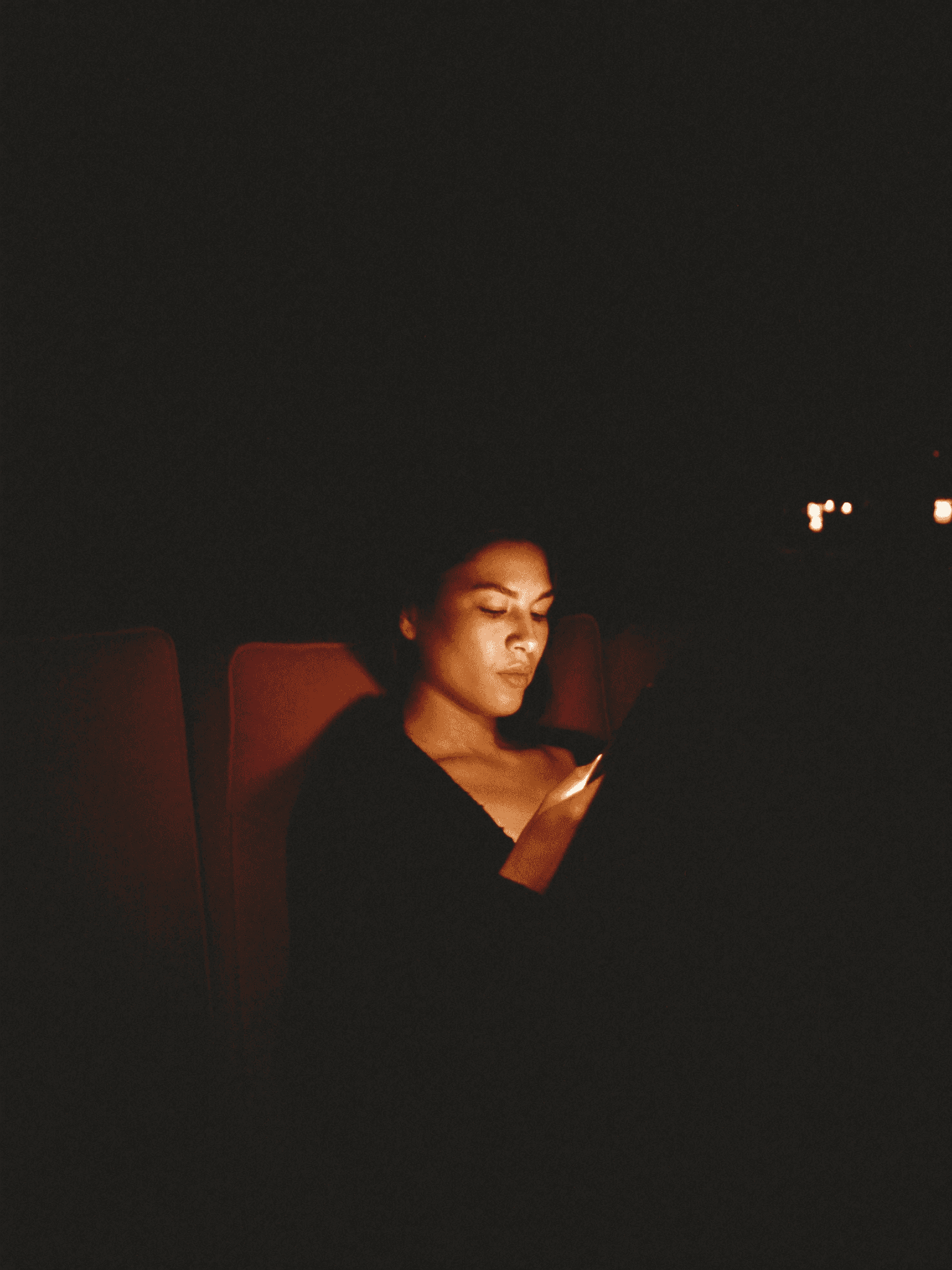 A woman at 11pm, reaching for her phone in the warm dark